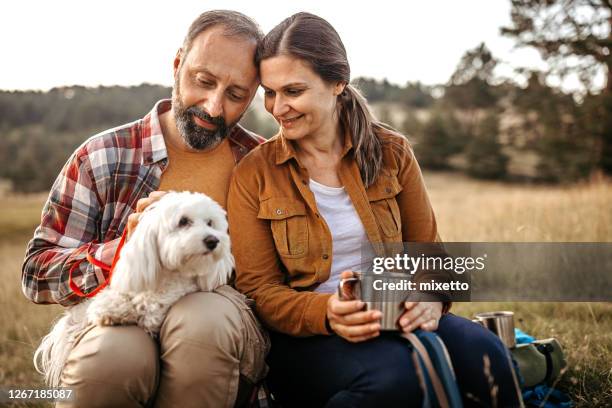 couple with pet dog relaxing while hiking at forest - cute dog with man stock pictures, royalty-free photos & images