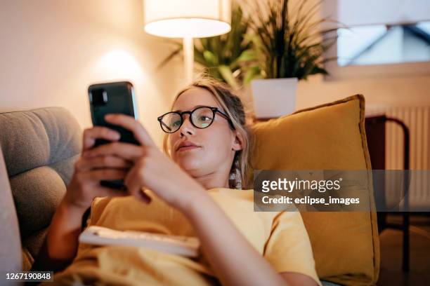 jonge vrouwen die tv thuis letten - lying down stockfoto's en -beelden