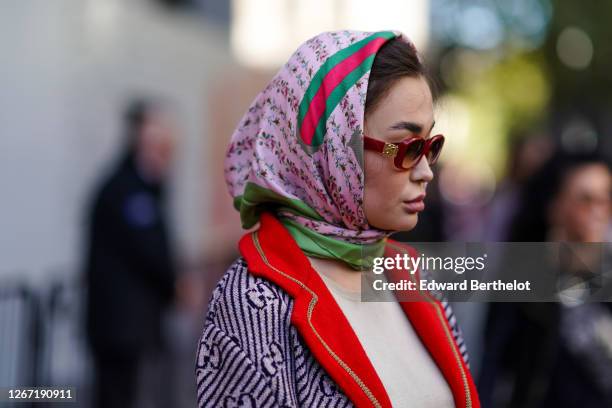 Guest wears burgundy sunglasses, a pink Gucci scarf over the head, during London Fashion Week September 2019 on September 13, 2019 in London, England.