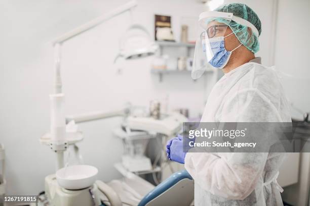 side view of male dentist in protective workwear at dental clinic - operating gown stock pictures, royalty-free photos & images