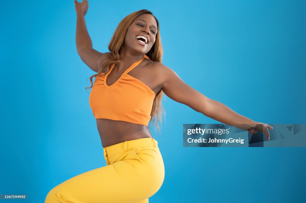 Portrait of casual mid 20s black woman smiling and dancing