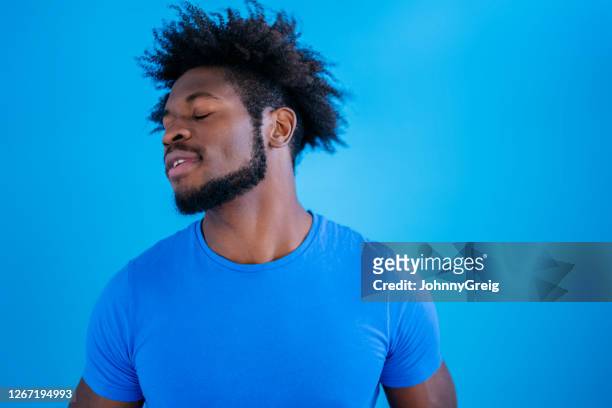 studio shot of young black man looking away with eyes closed - royal blue stock pictures, royalty-free photos & images