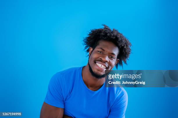 informal studio shot of early 20s black man in blue t-shirt - royal blue stock pictures, royalty-free photos & images