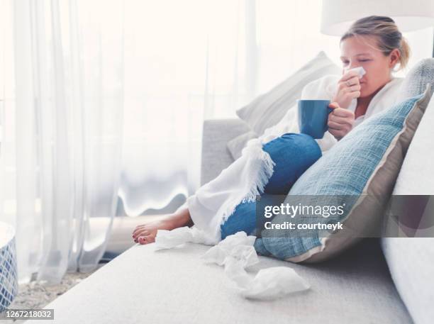 woman sitting on the sofa with a cold, flu or allergy. - aussie flu stock pictures, royalty-free photos & images