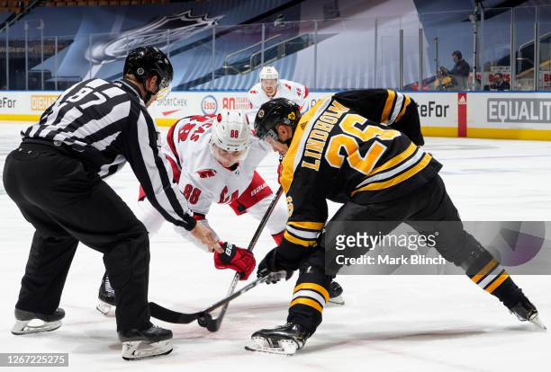 Linesman Devin Berg drops the puck for Martin Necas of the Carolina Hurricanes and Par Lindholm of the Boston Bruins to face off during the second...