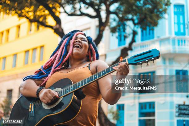 donna con acconciatura rastafariana che suona la chitarra acustica per strada - brazilian culture foto e immagini stock