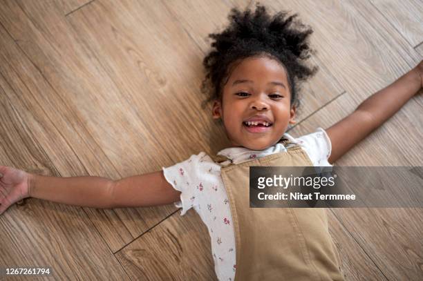 mixed race girls laying down on floor in living room. - girl lying down stock pictures, royalty-free photos & images