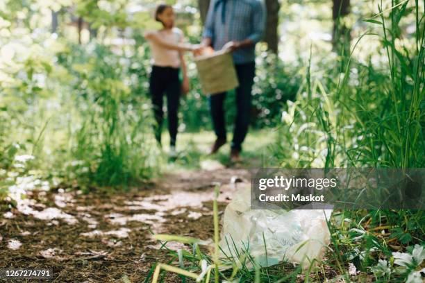 low section of father and daughter collecting garbage at garden center - permanence stock pictures, royalty-free photos & images