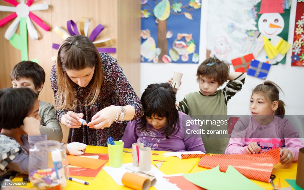 Cheerful school children with special needs sitting at a desk in primary school class