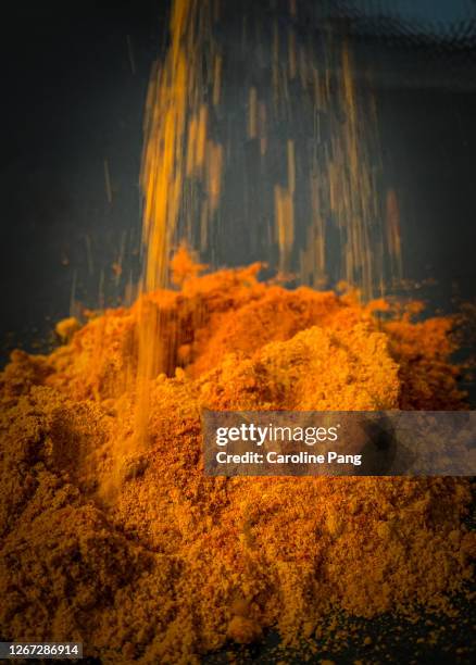 pouring a mix of curry and chilli powder. - chilli powder stock-fotos und bilder