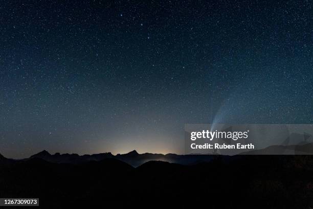 a comet visible on the sky on at night over the mountain landscape - cometa imagens e fotografias de stock