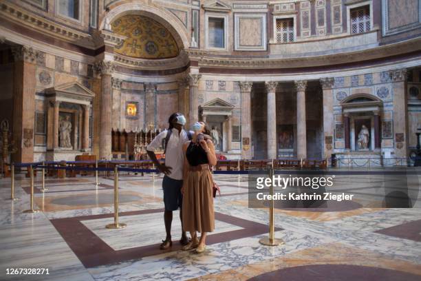 couple enjoying the empty pantheon in rome, wearing protective face masks during covid-19 pandemic - corona landmarks stockfoto's en -beelden