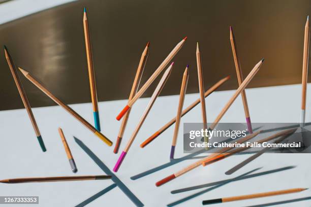 sharpened wooden colouring pencils falling onto a white surface casting shadows - strumento per scrivere foto e immagini stock