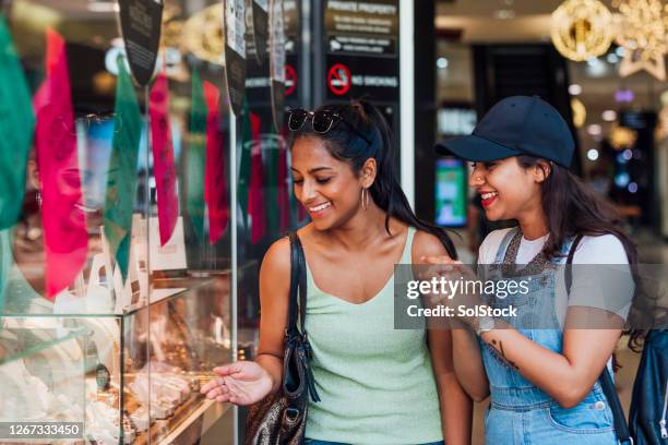 twee etnische vrouwelijke vrienden die in het winkelvenster richten - australia shopping stockfoto's en -beelden