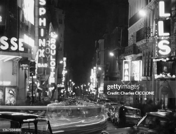 Enseignes de sex-shops dans une rue du quartier de Pigalle de nuit à Paris, circa 1970, France.