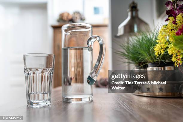 water glass with carafe on a kitchen table in a kitchen - carafe stock pictures, royalty-free photos & images