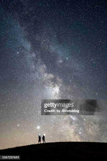 via lattea con due persone in silhoutte che si fanno luce col cellulare - cellulare stock pictures, royalty-free photos & images