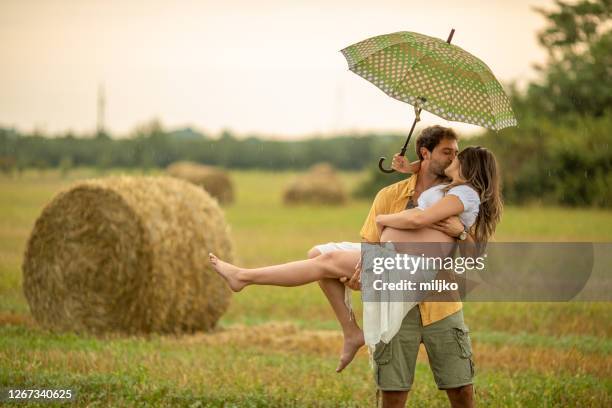 beautiful young couple at stubble field while expecting baby - rain kiss stock pictures, royalty-free photos & images