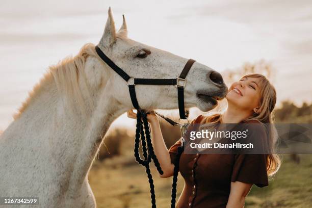white horse kissing young blond woman - horse stock pictures, royalty-free photos & images