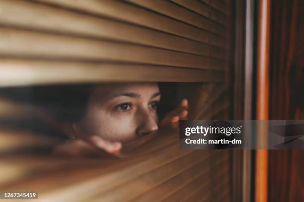 lockdown durante la pandemia di covid-19 - woman peeking through blinds foto e immagini stock