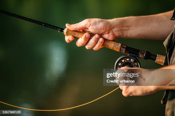 uomo con una pesca rotante sul fiume - fishing reel foto e immagini stock