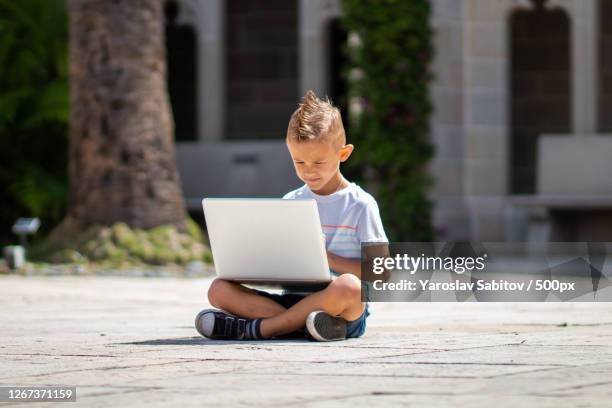 young boy sitting outdoors on ground with laptop, west palm beach, united states - kid sitting stock pictures, royalty-free photos & images