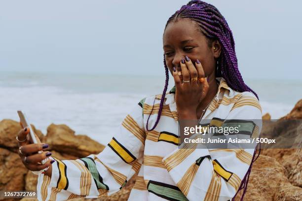 black woman using mobile phone while standing at beach against clear sky, kasoa, ghana - african girls on beach stock pictures, royalty-free photos & images