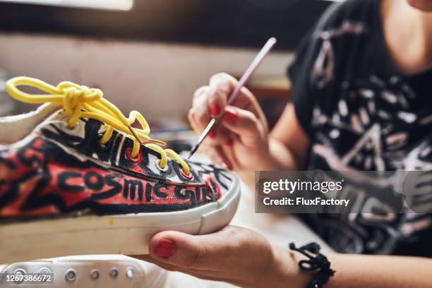 female artist with a paintbrush painting sneakers - multi coloured shoe imagens e fotografias de stock