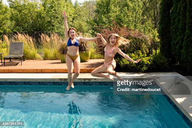 de pret van het water voor twee neven die in binnenplaatspool springen. - tween girl swimsuit stockfoto's en -beelden