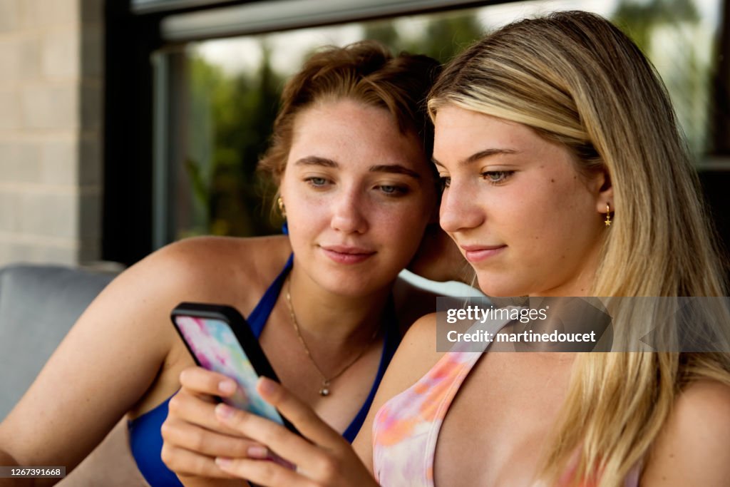 Two cute cousins relaxing backyard with mobile phone.