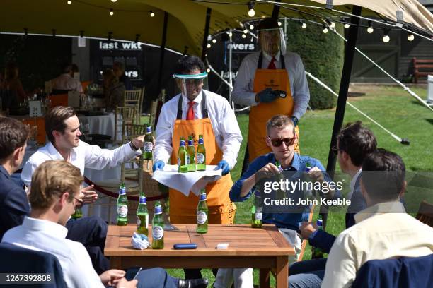 Bar staff wearing face shields serve a group of friends bottles of Peroni beer during the London Concours at Honourable Artillery Company on August...