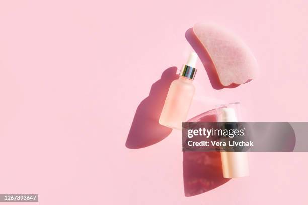 top view of  jars with various creams , liquid gel or serum drop with pipette placed on pink background - serum sample stock pictures, royalty-free photos & images