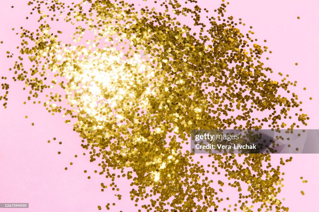 Golden sparkles on pink pastel trendy background. Festive backdrop for your projects.