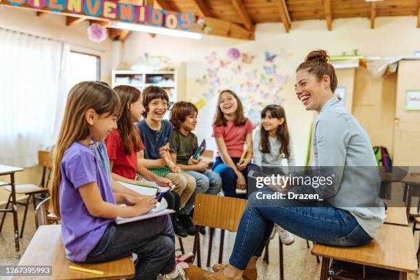 female latina teacher talking to kids who are back to school after covid-19 break - spanish language stock pictures, royalty-free photos & images