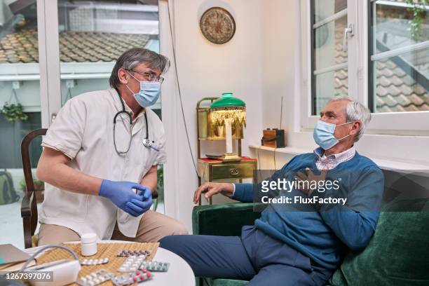 man complaining about chest pain to his doctor - respiratory disease stock pictures, royalty-free photos & images