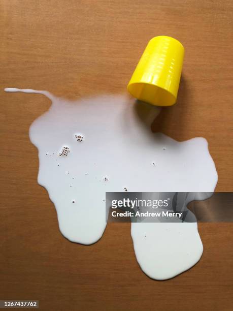 spilt milk and yellow cup on wooden table - goutte lait photos et images de collection