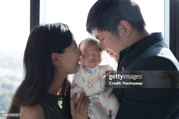 parents holding one month old baby with pacifier, inside a room in tall building - small man and tall woman stock pictures, royalty-free photos & images