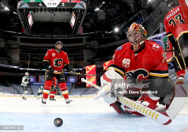 Goaltender David Rittich and Derek Forbort of the Calgary Flames look at the puck after it went in the net on a shot by Joe Pavelski of the Dallas...