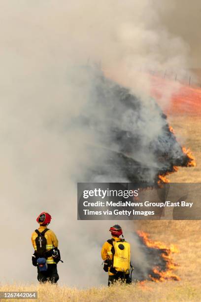 Fairfield Fire Fighters Robbie Engell, left, and Danny Torres watch over a slow moving wildfire as it burns on a hillside behind homes in the Rolling...