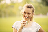 Sportive Woman eating a protein bar after outdoor workout - Closeup face of young blonde sporty woman resting while biting a nutritive bar