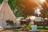 Outdoor kitchen equipment and wooden table set with field tents group in camping area at natural parkland