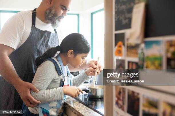 father helping his daughter with cooking on the stove - auckland food bildbanksfoton och bilder