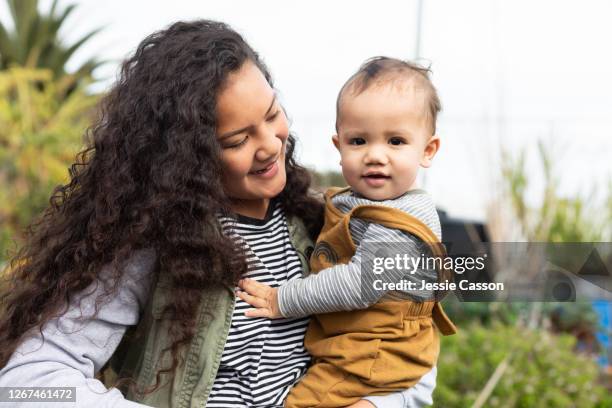 older girl with baby in garden - polynesische etniciteit stockfoto's en -beelden
