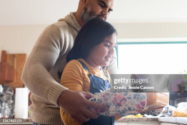 father helps daughter to take baking out of oven - leanincollection father photos et images de collection