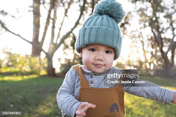 baby walking through park in beautiful light - gorro de invierno fotografías e imágenes de stock