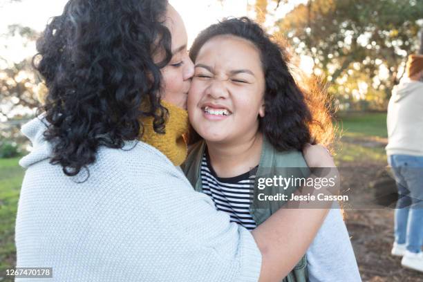 close-up of mother kissing daughter but daughter screws up face - beautiful polynesian women - fotografias e filmes do acervo