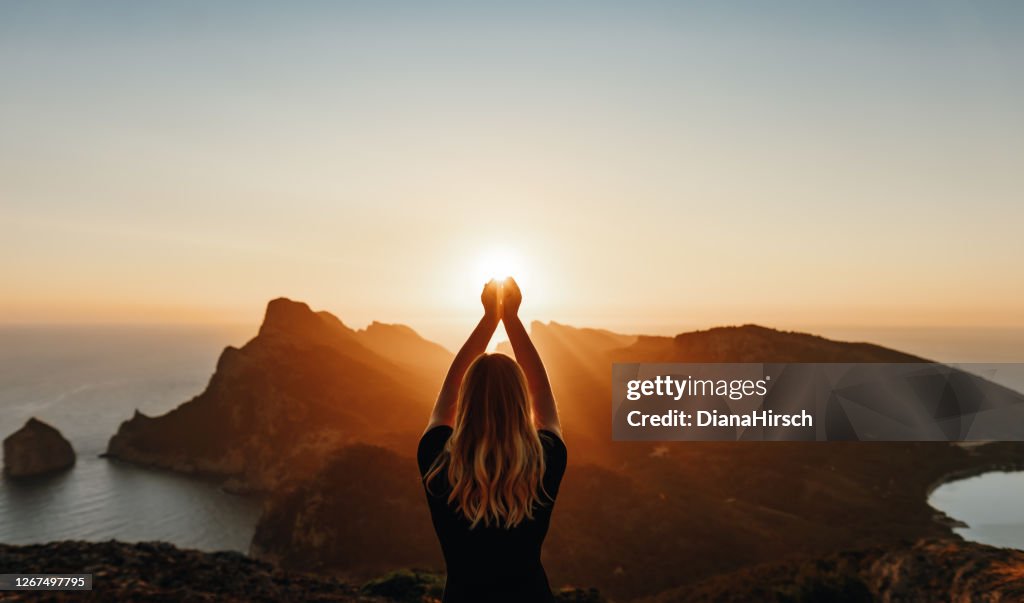 Mujer joven en pose espiritual sosteniendo la luz