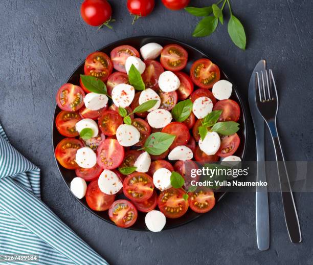 caprese salad with tomatoes and mozzarella cheese on black background. - caprese salad stock pictures, royalty-free photos & images