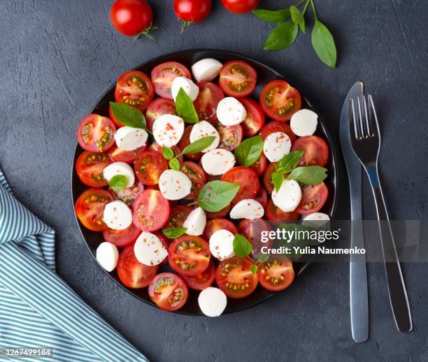 caprese salad with tomatoes and mozzarella cheese on black background. - caprese salad overhead stock pictures, royalty-free photos & images