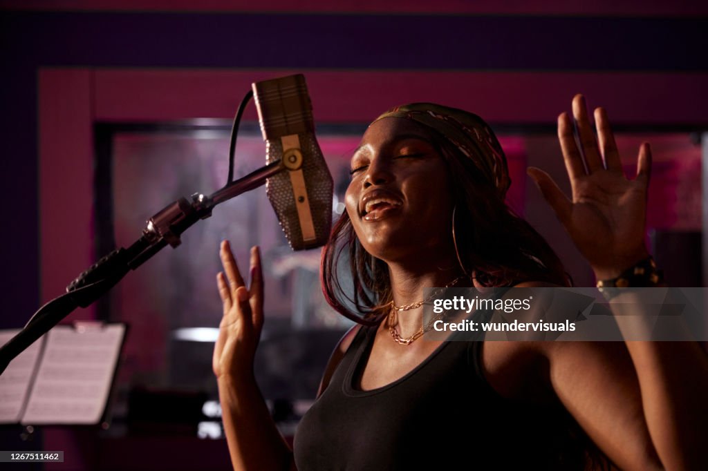 Cantante afroamericana che registra la voce al microfono nella cabina di registrazione dello studio musicale